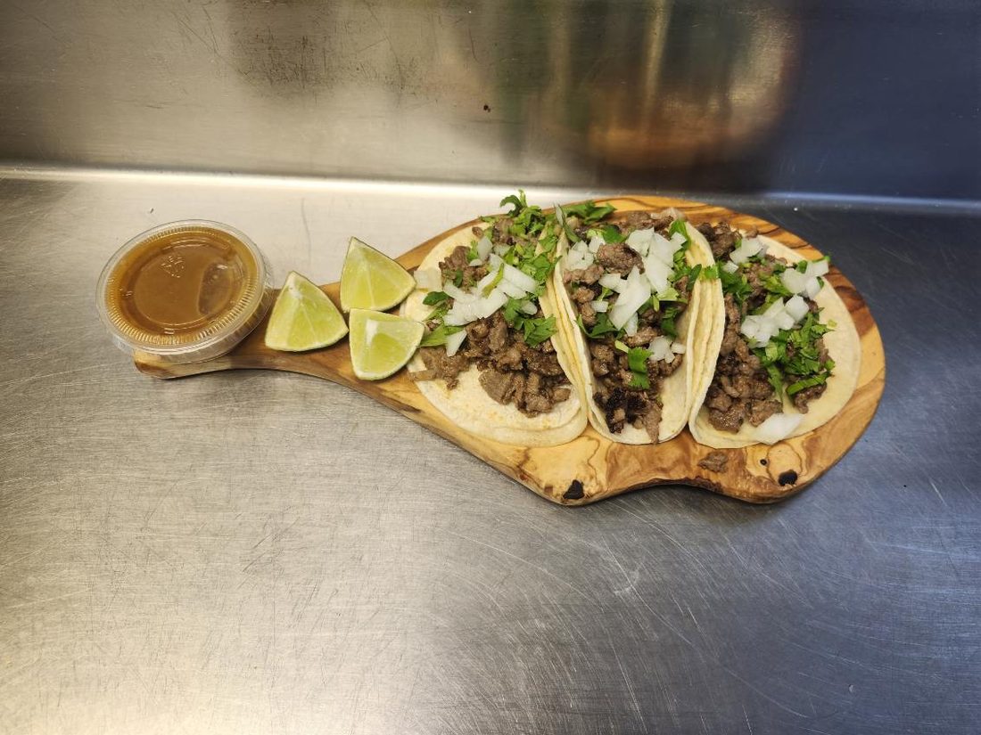 Tacos with consomé on a wooden serving board.